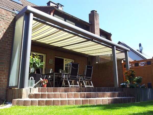 Moderne Terrassenüberdachung mit Markise und Gartenmöbeln an einem Einfamilienhaus.